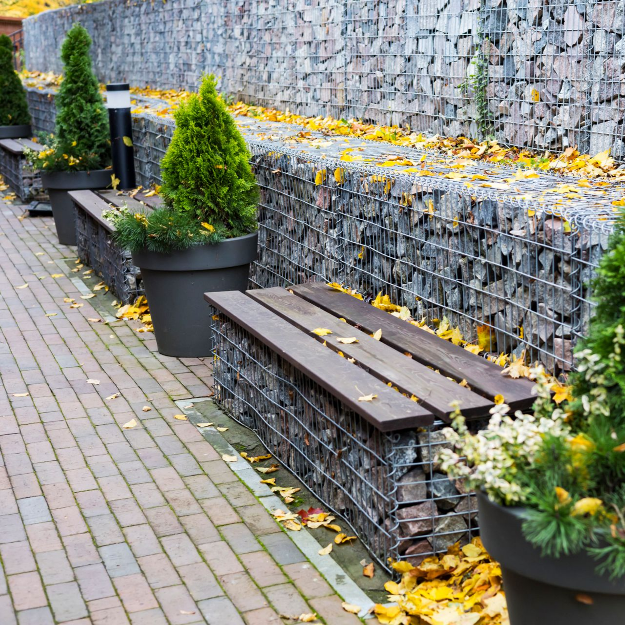 Bancs en pierre et grillage avec sièges en bois le long d'un mur en pierre, feuilles d'automne.