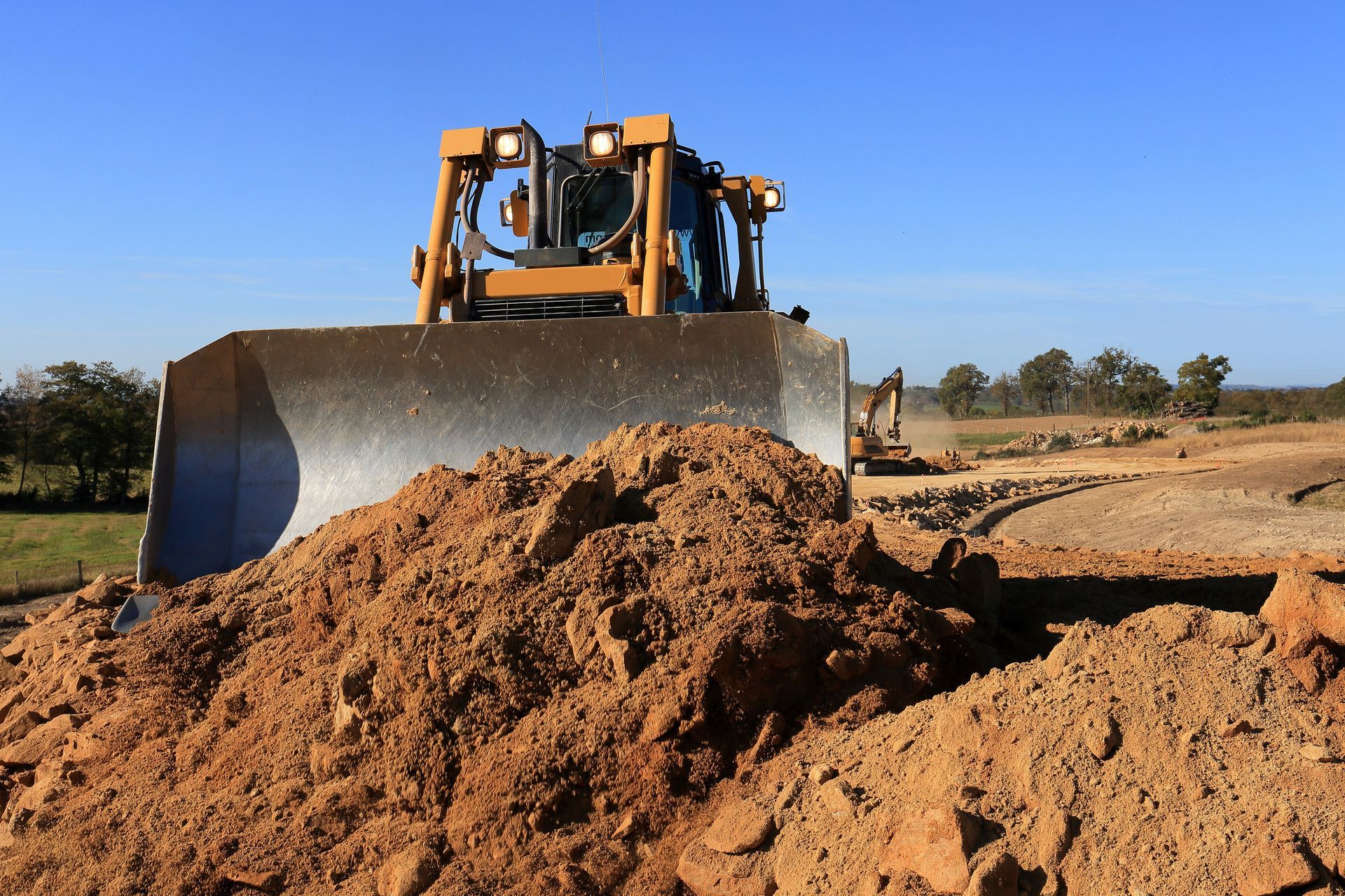 Bulldozer poussant de la terre sur un chantier de construction ; ciel bleu.