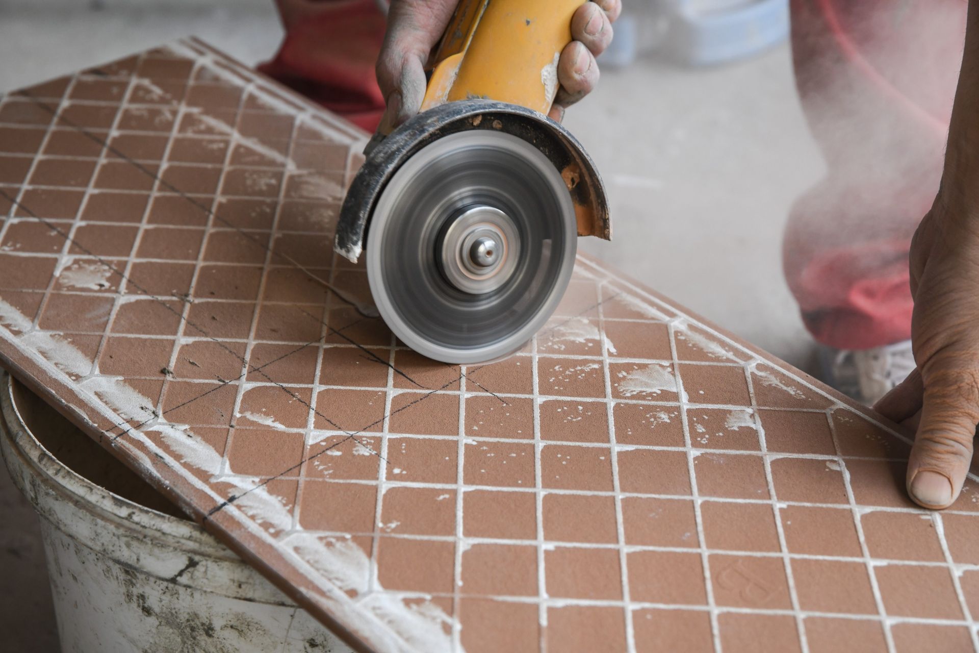 Una persona está cortando un azulejo con una amoladora.
