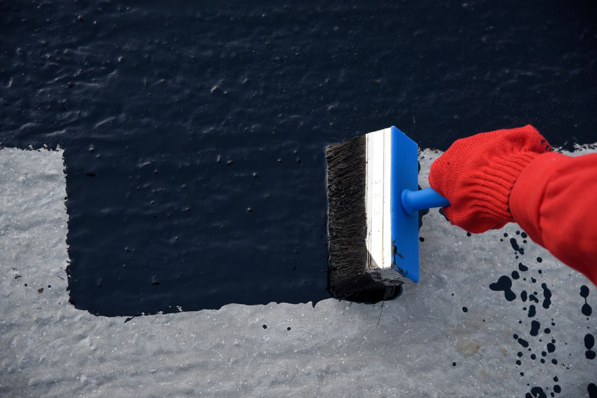 Una persona que lleva un guante rojo sostiene un cepillo azul.