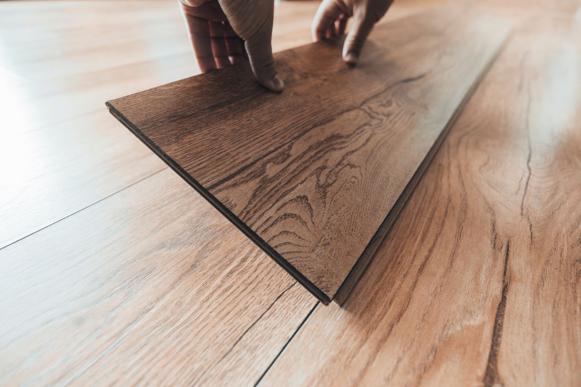 Una persona está colocando un trozo de madera sobre un piso de madera.