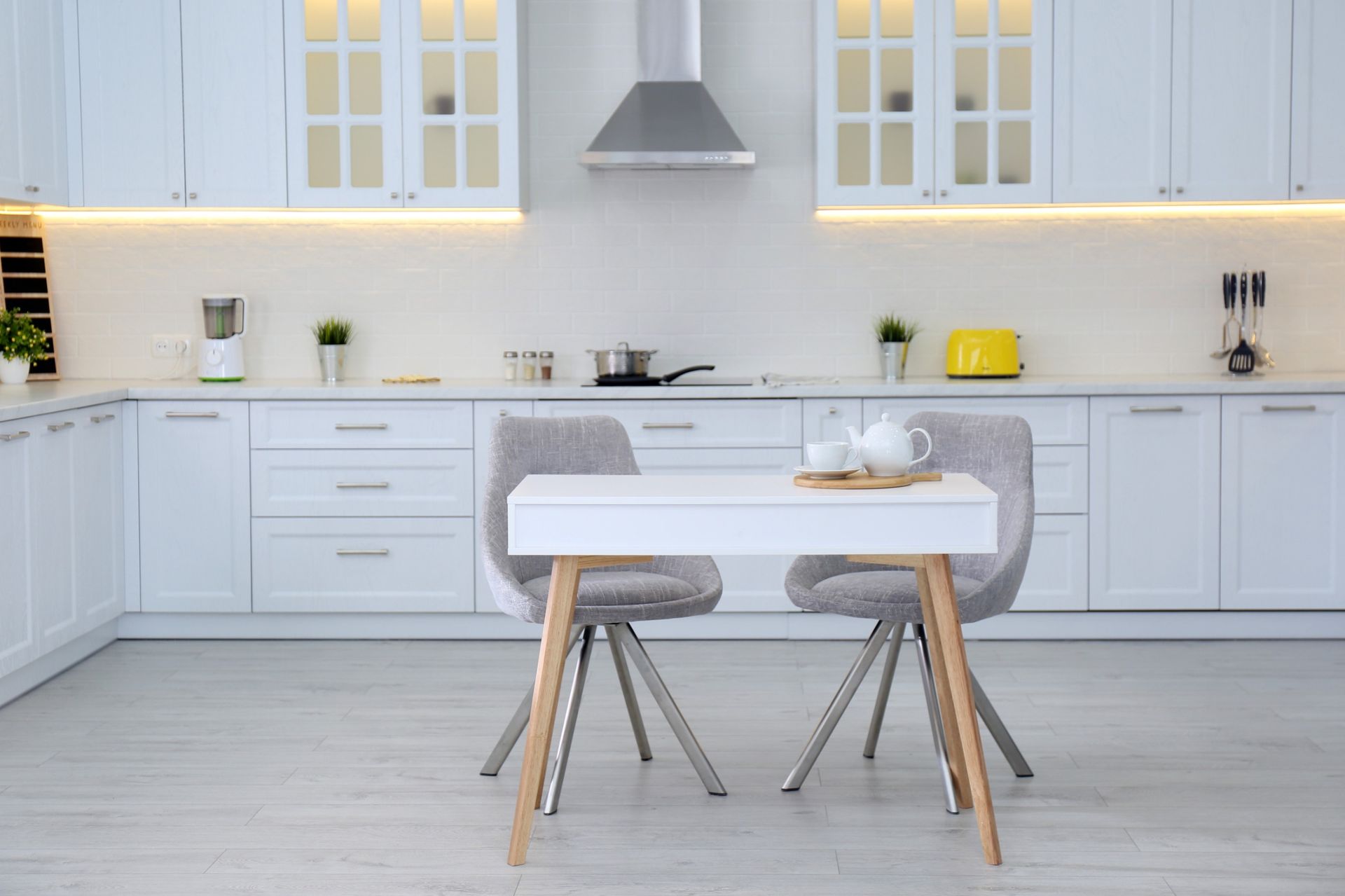 Una cocina con gabinetes blancos y una mesa y sillas.