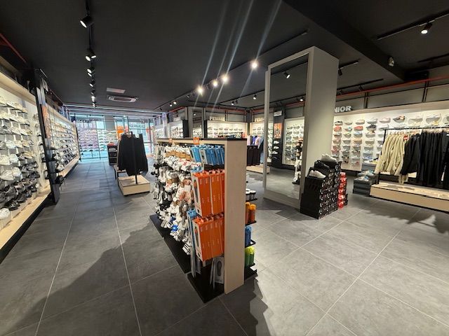 Un magasin de détail de chaussures et de vêtements avec des étagères bien organisées, des présentoirs de produits et des portants à vêtements.