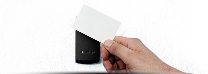 Une main actionne un interrupteur sur un mur blanc avec une plaque de finition noire.