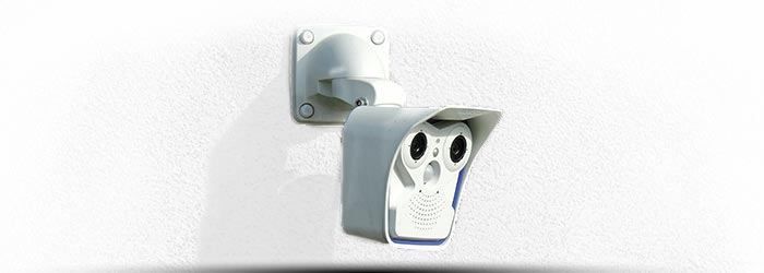 Caméra de sécurité murale avec objectifs infrarouges sur un mur blanc