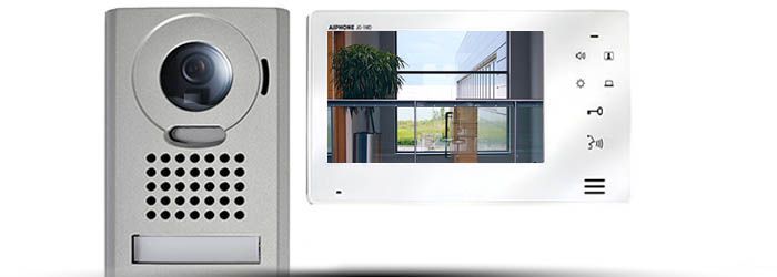 Interphone vidéo mural avec caméra, grille de haut-parleur et petit écran affichant l'entrée du bâtiment