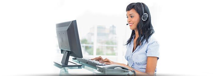 Une femme portant un casque audio tape sur un ordinateur de bureau dans un bureau lumineux