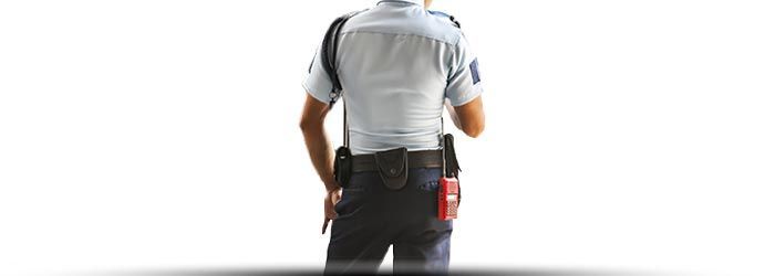 Vue de dos d'un ouvrier en chemise grise et pantalon foncé, se détachant sur un fond blanc.
