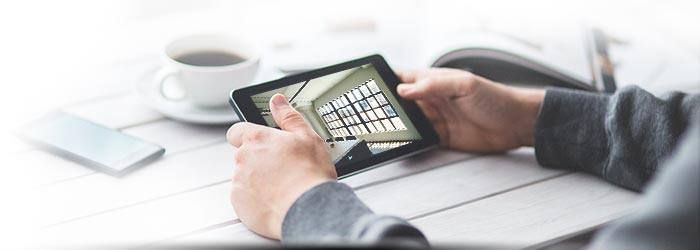 Des mains tenant un smartphone avec un clavier à l'écran à côté d'une tasse de café et un autre téléphone sur une table blanche