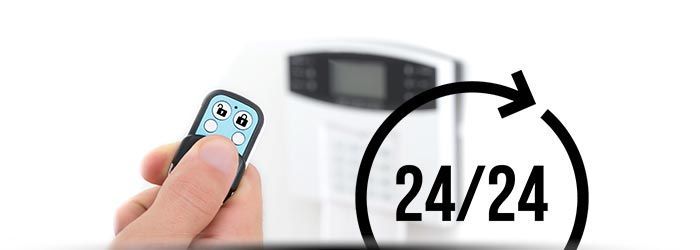 Main tenant une télécommande pointant vers un radiateur blanc avec une icône d'horloge 24/24
