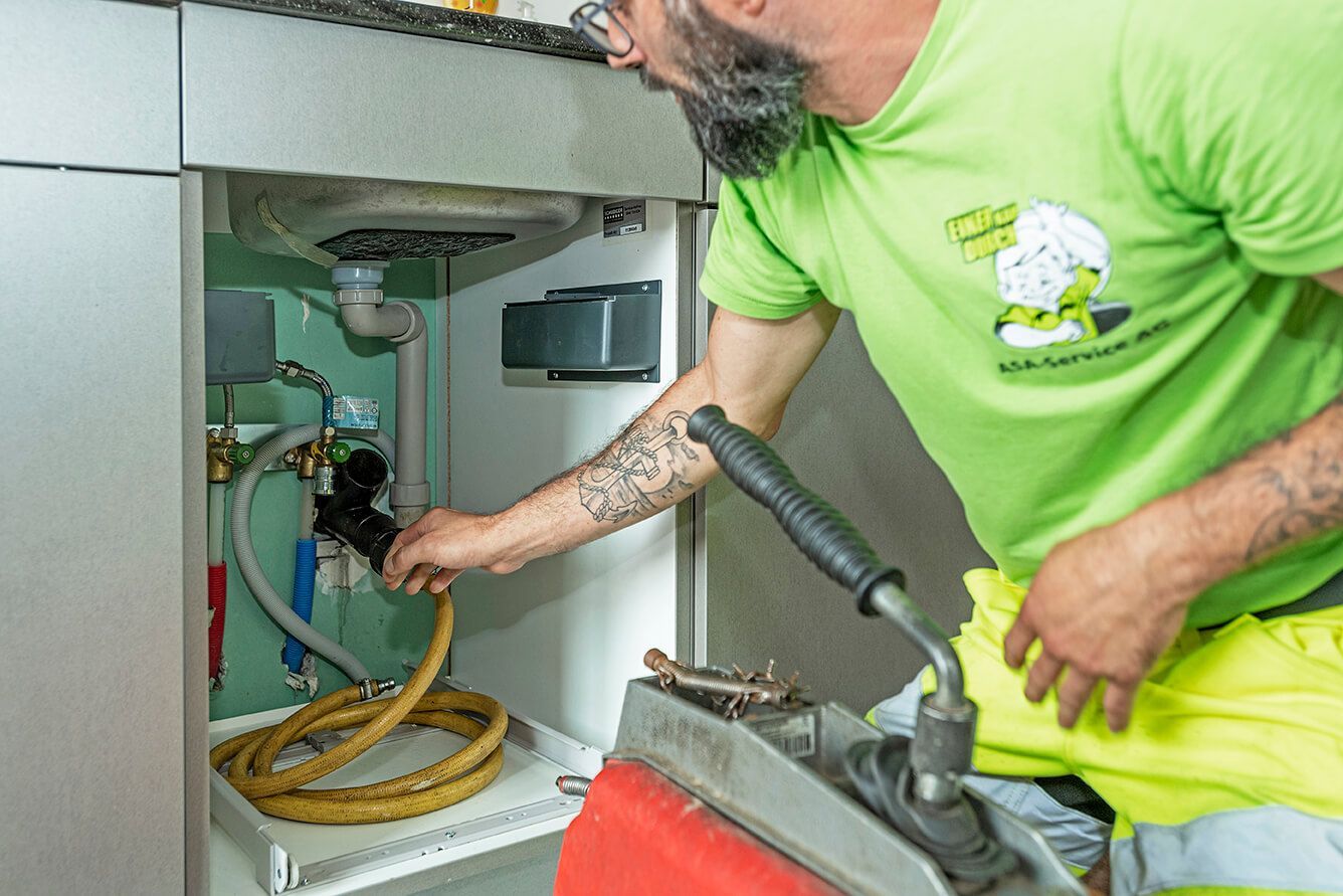 Ein Mann in einem grünen Hemd arbeitet an einem Waschbecken.