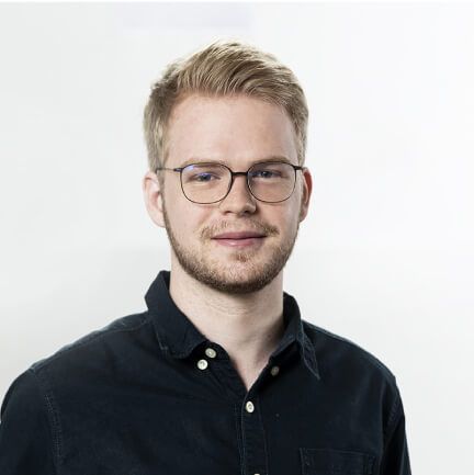 Ein junger Mann mit Brille und Bart trägt ein schwarzes Hemd.