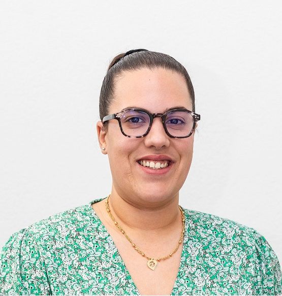 Eine Frau mit Brille und grünem Hemd lächelt in die Kamera.