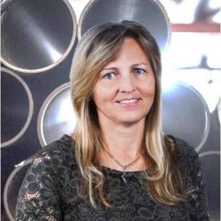 Eine Frau steht vor einer Wand aus Metallrohren.