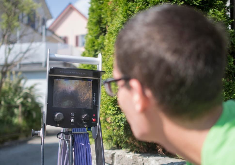 Ein Mann schaut vor einem Haus in eine Kamera.