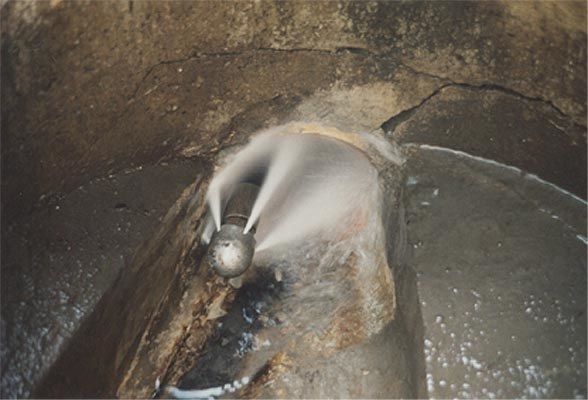 Ein Mann steht neben einem Gullydeckel, an dem eine Kamera befestigt ist.