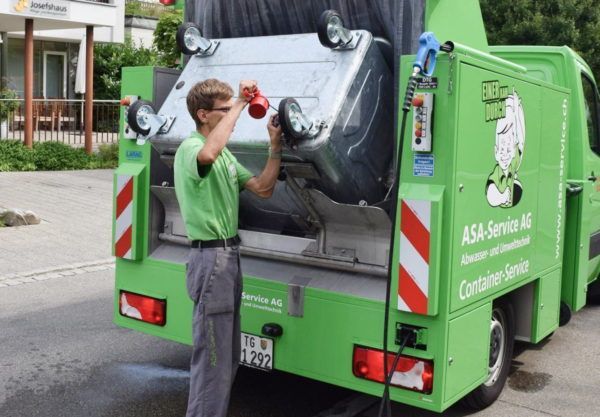 Ein Mann steht vor einem grünen Müllwagen