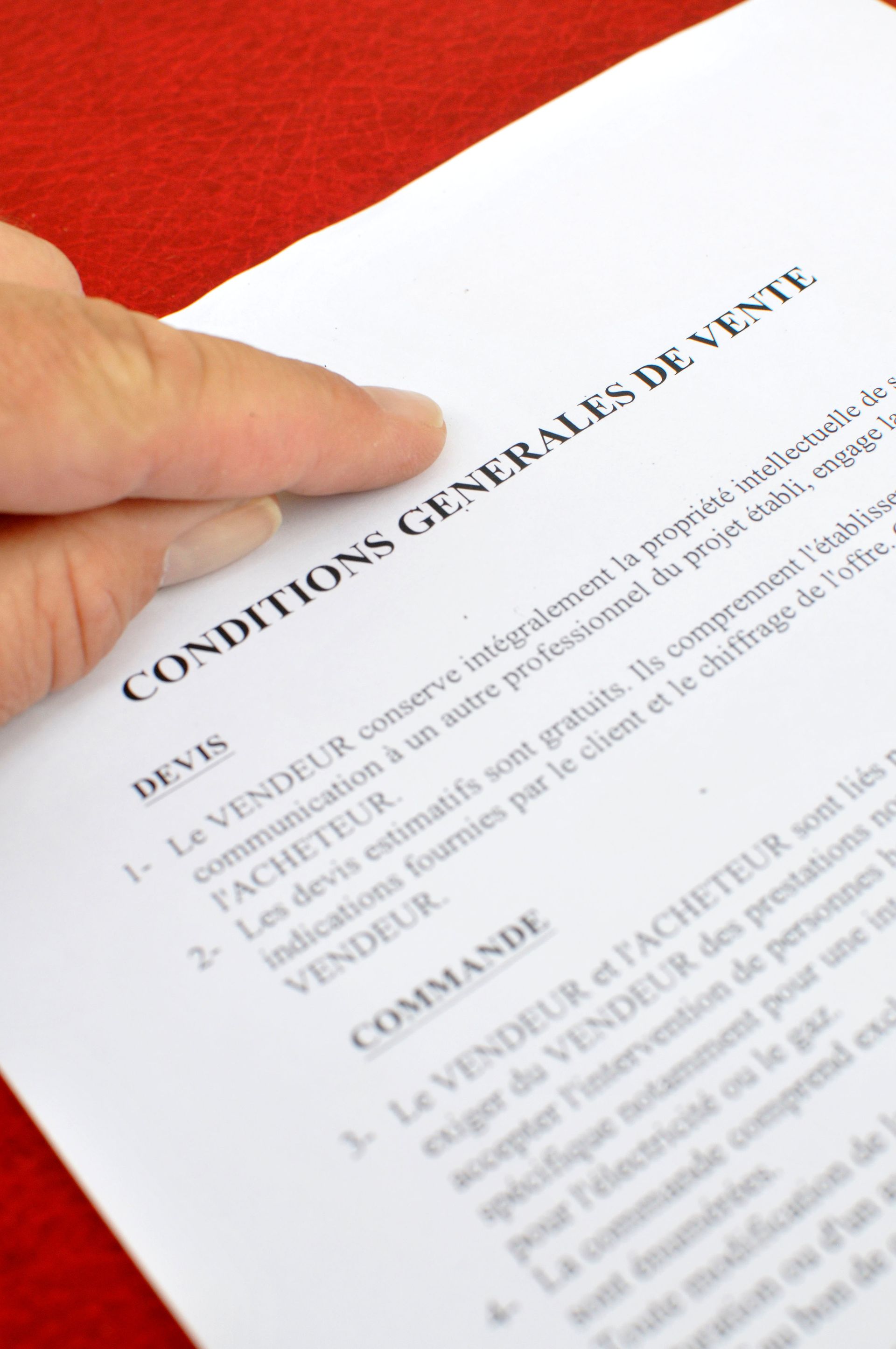 Le doigt d'une personne pointant vers un document intitulé conditions générales de vente.