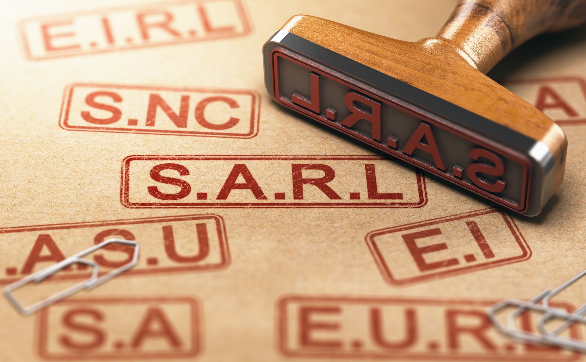 Tampon en bois portant l'inscription SARL, entouré d'autres abréviations d'entités commerciales sur papier.