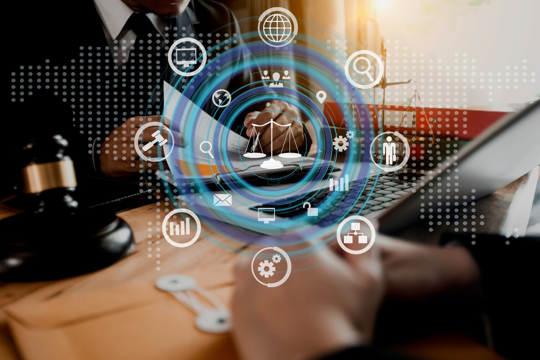 Deux personnes travaillent sur un ordinateur portable avec une superposition numérique de symboles juridiques et un maillet sur un bureau.