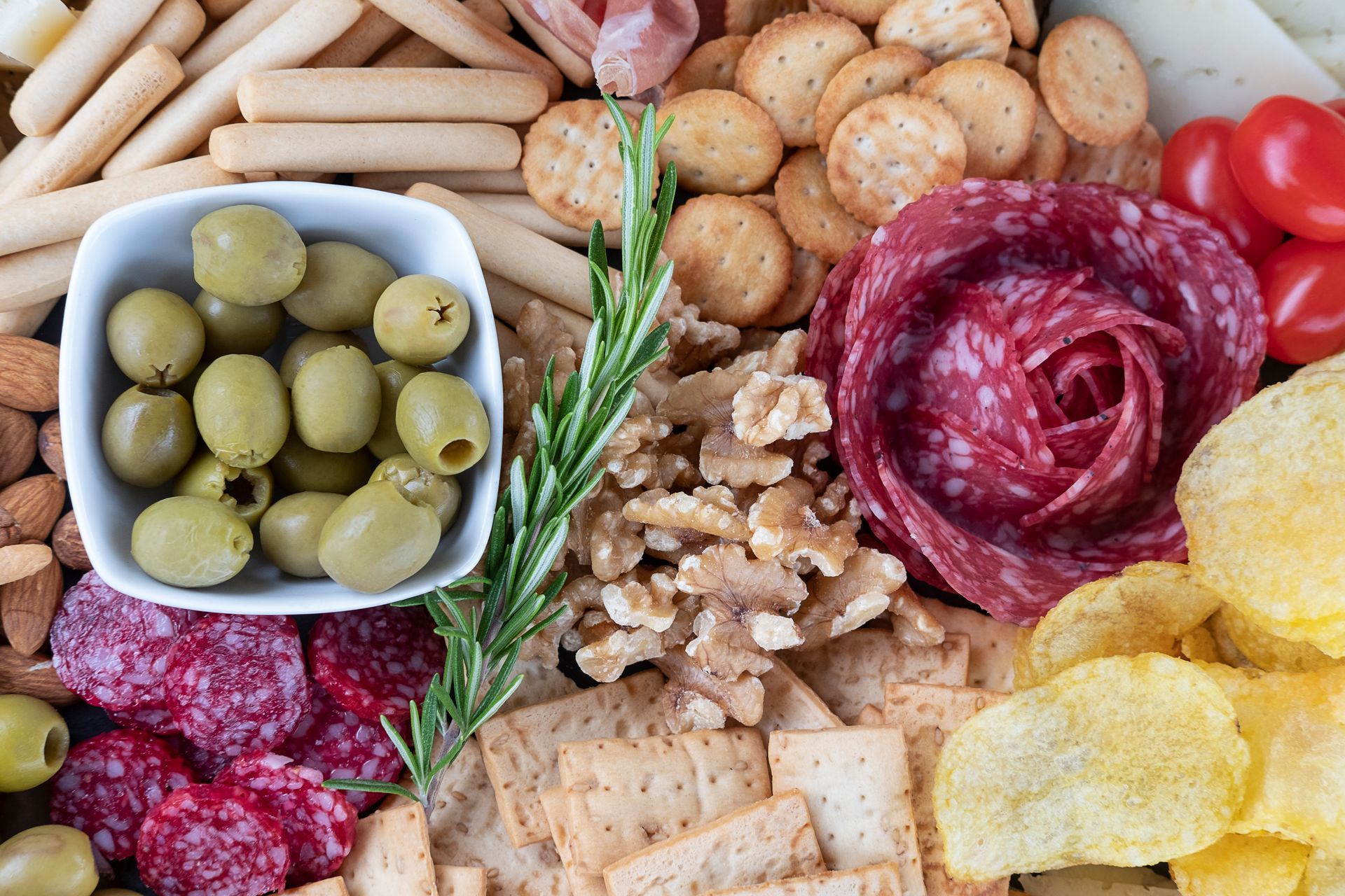 Un plateau apéro composé d'olives, de charcuterie et de snacks