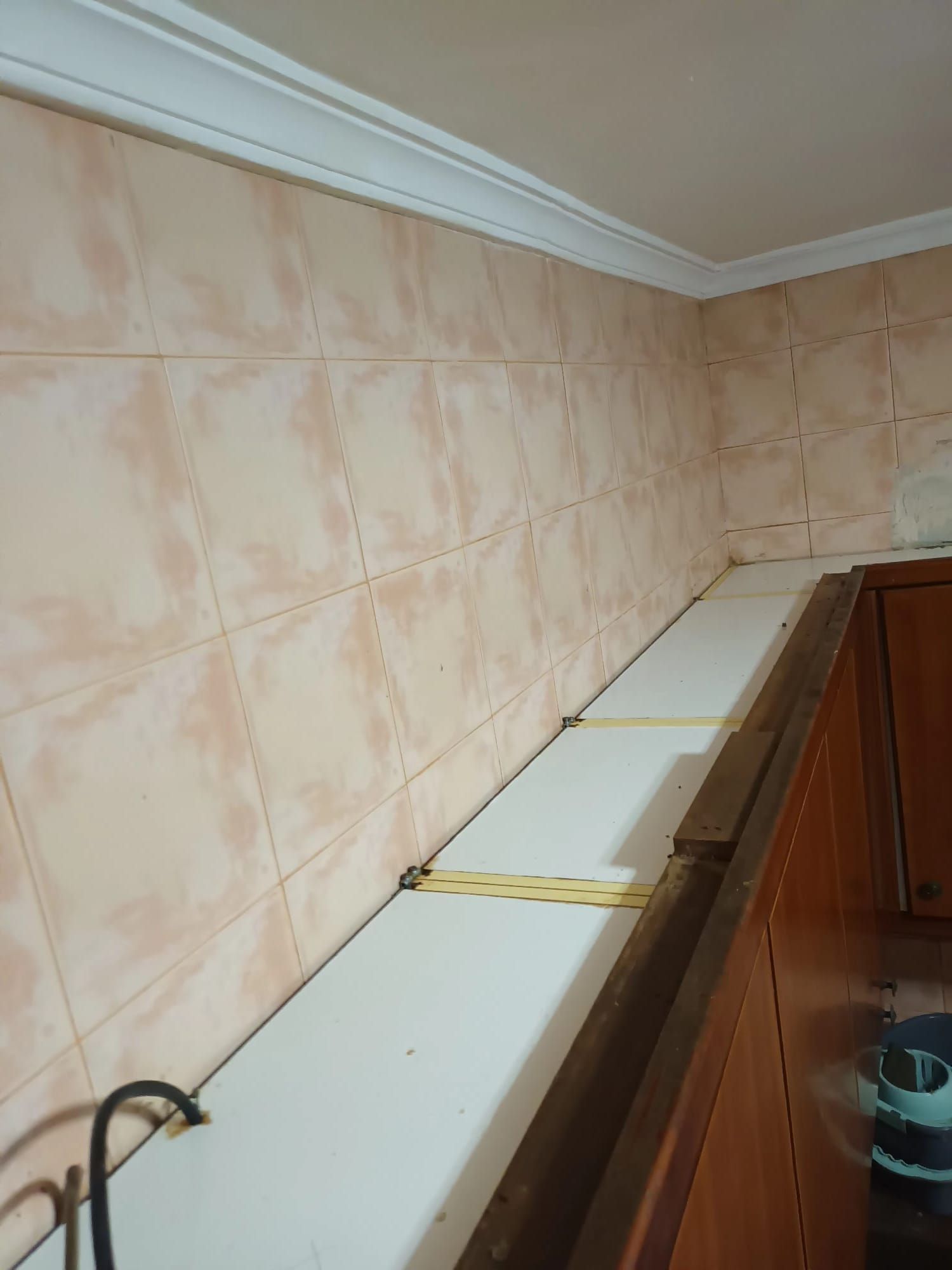 Estante blanco entre pared de azulejos y armarios.