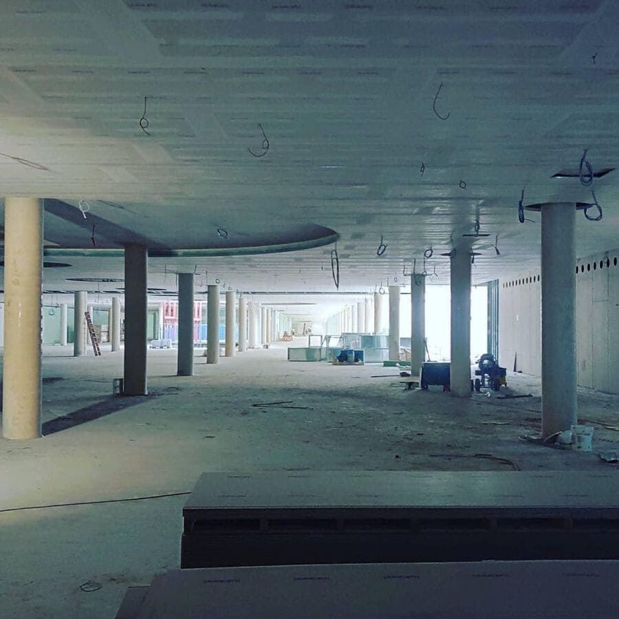 Obra interior con pilares de hormigón y techo sin terminar.