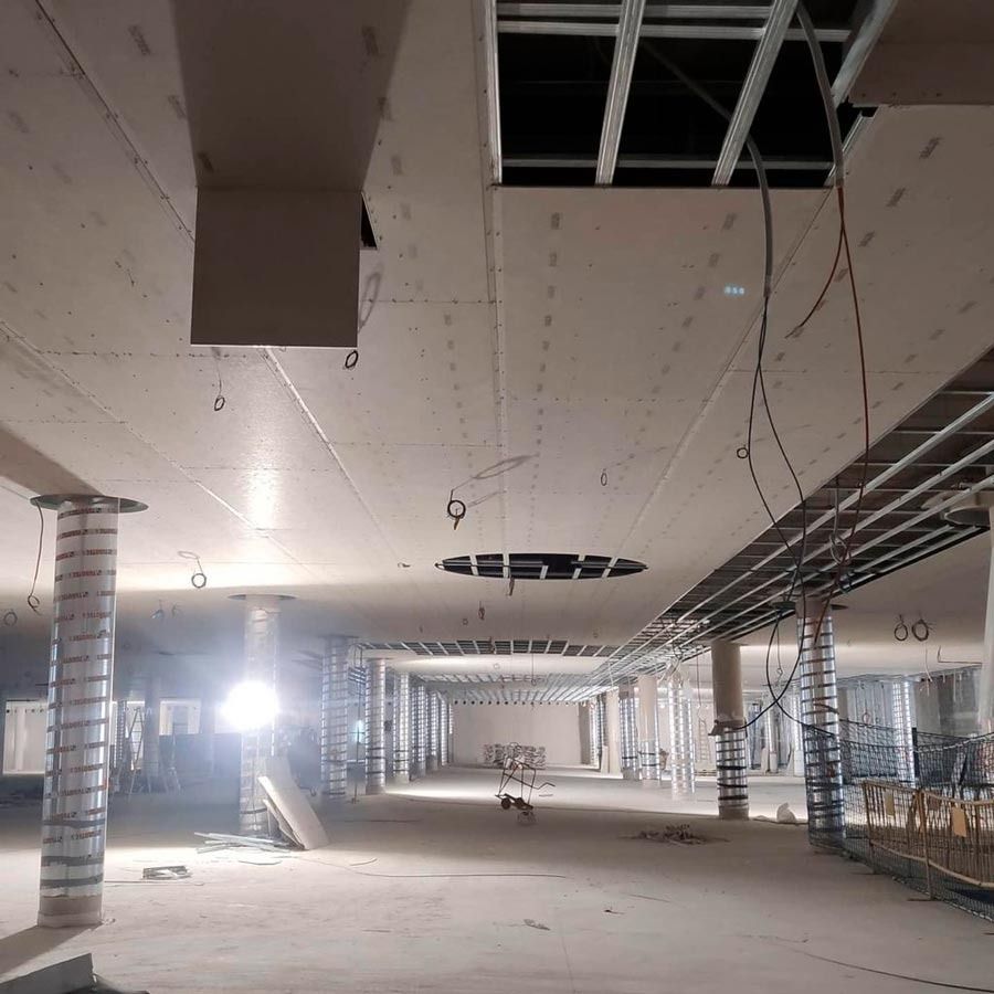 Interior de una obra en construcción con infraestructura de techo expuesta, columnas de soporte y pisos sin terminar.