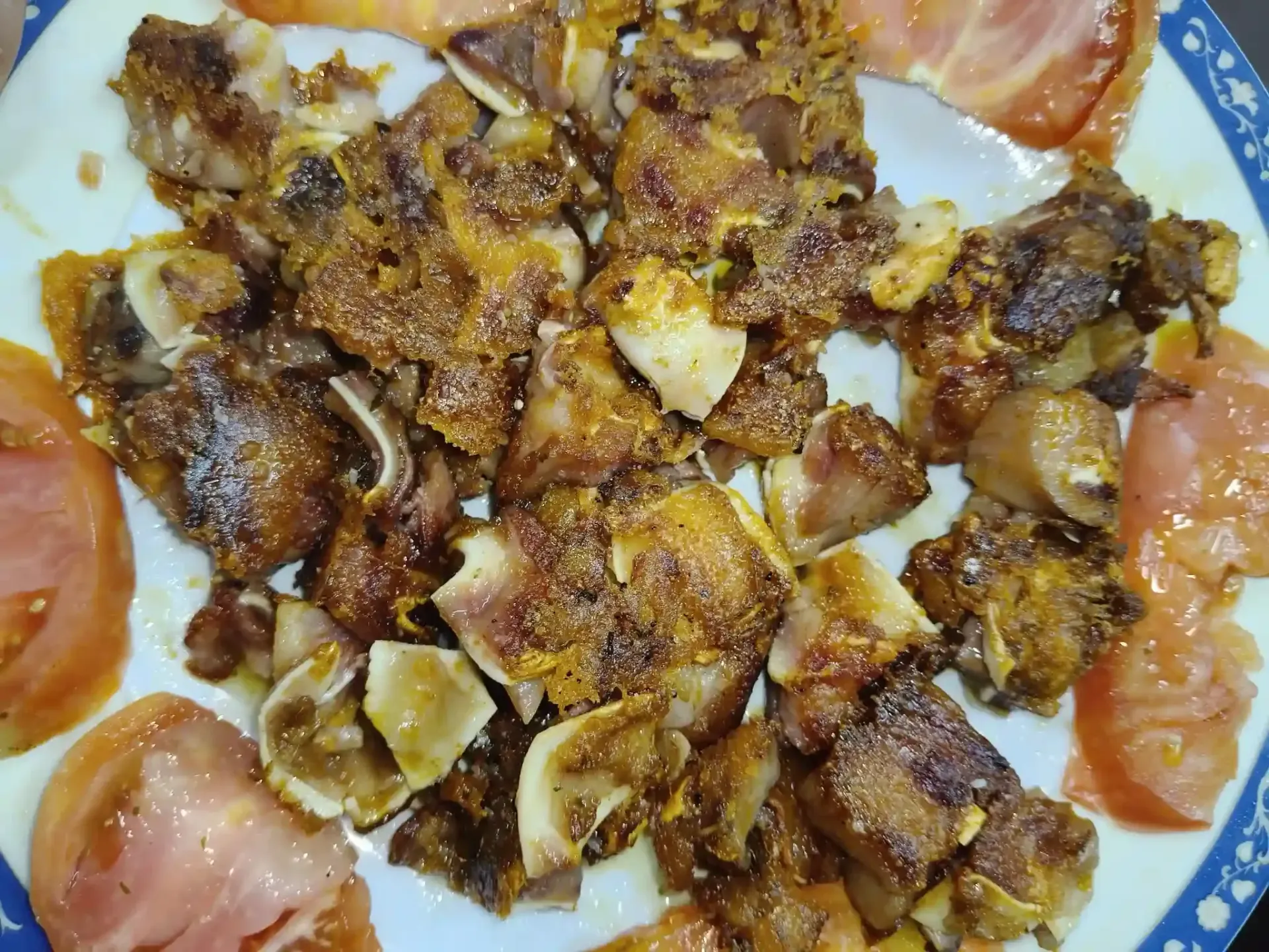 Trozos de carne fritos con tomates en rodajas en un plato blanco.