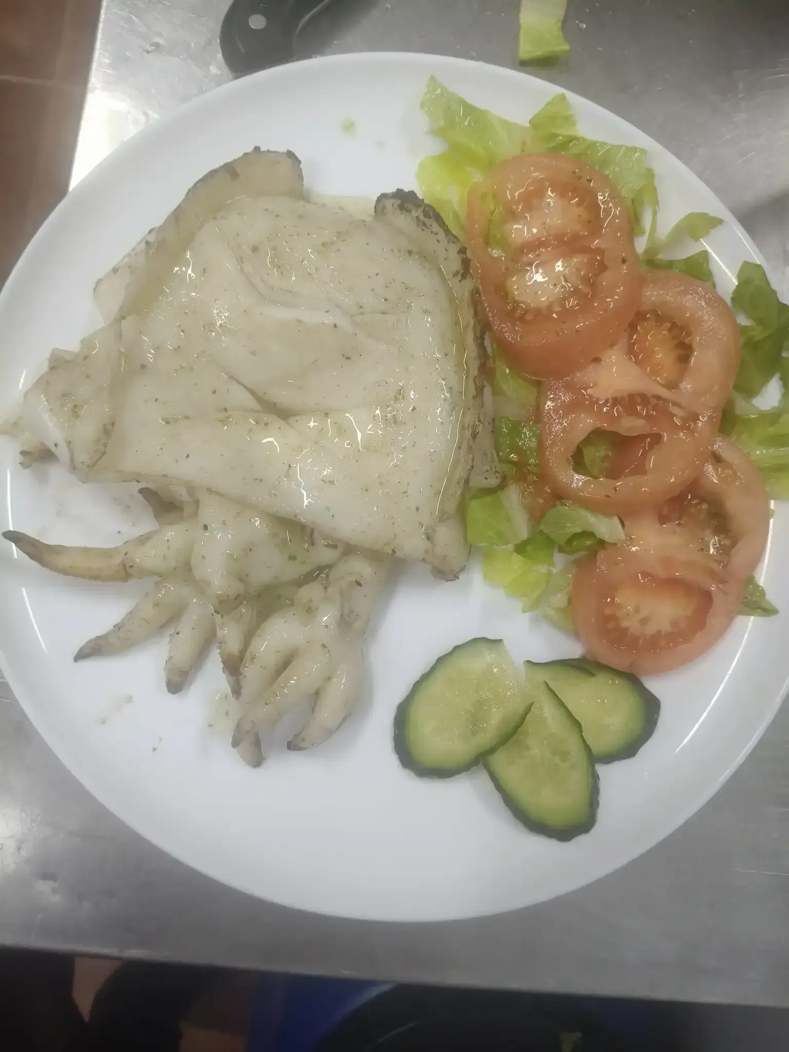Calamares a la plancha con ensalada y rodajas de pepino en un plato blanco.
