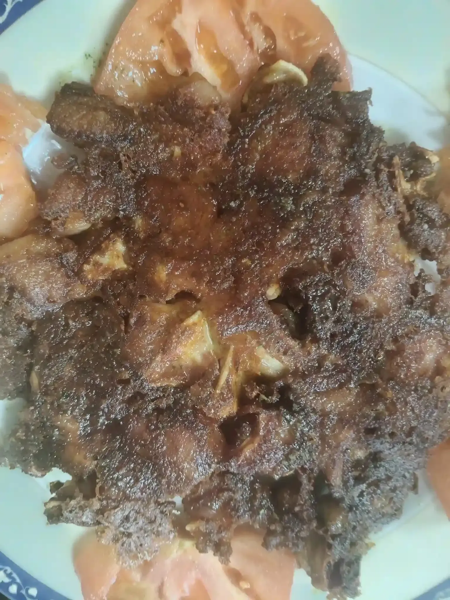 Pollo frito con rodajas de tomate en un plato blanco.