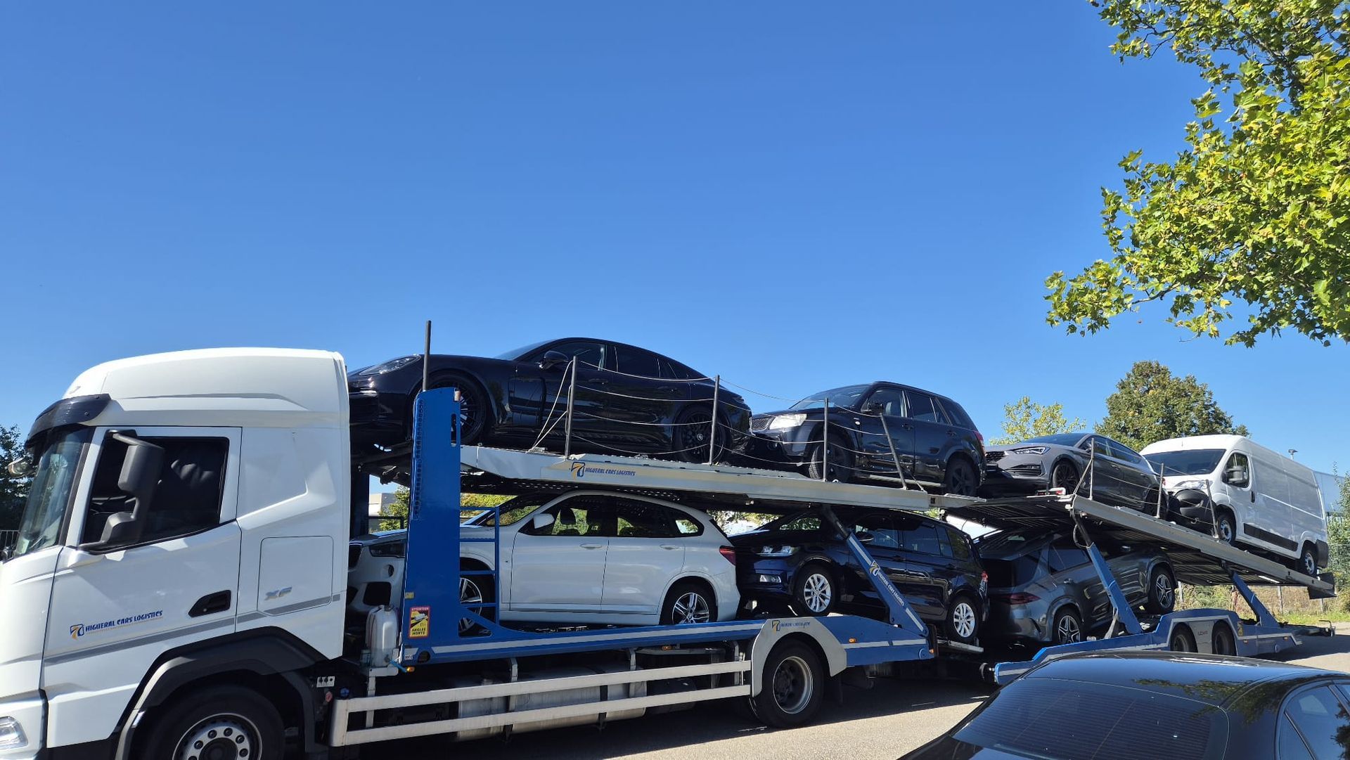 Camión transportador de automóviles que transporta varios vehículos en un día soleado.