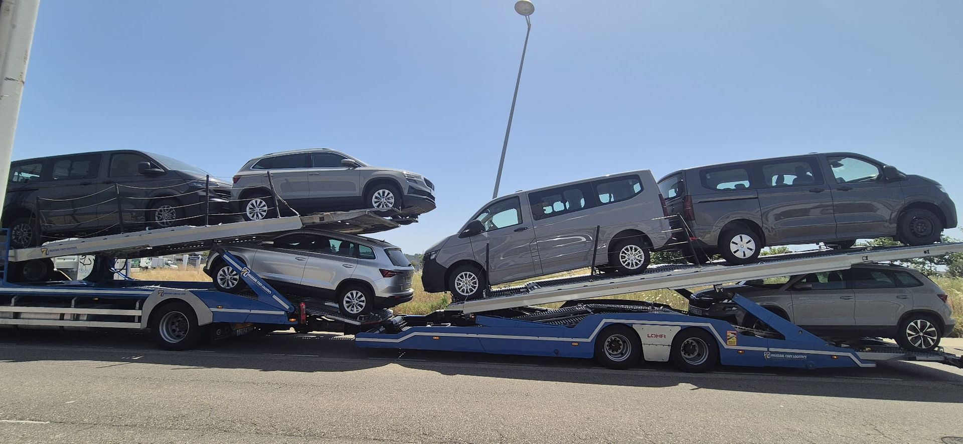 Un transportador de automóviles que transporta varios vehículos en un día soleado.