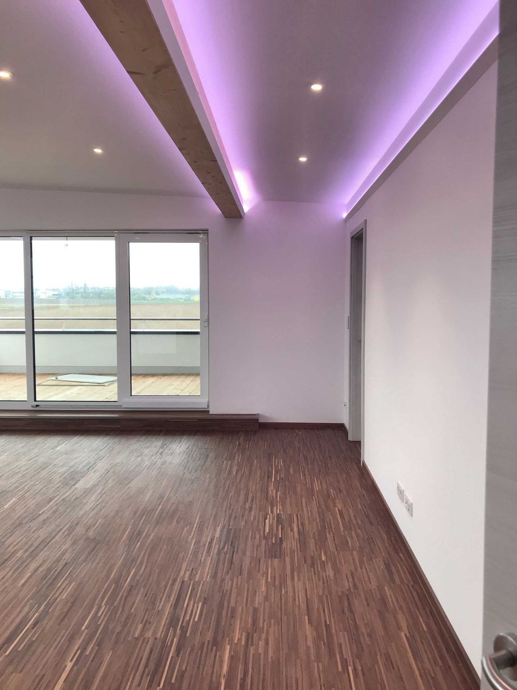 Ein leerer Raum mit einem Holzboden und einer lila Decke.