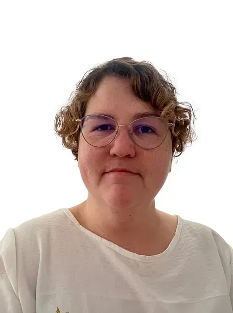 Una mujer que lleva gafas y una camisa blanca sonríe para la cámara.