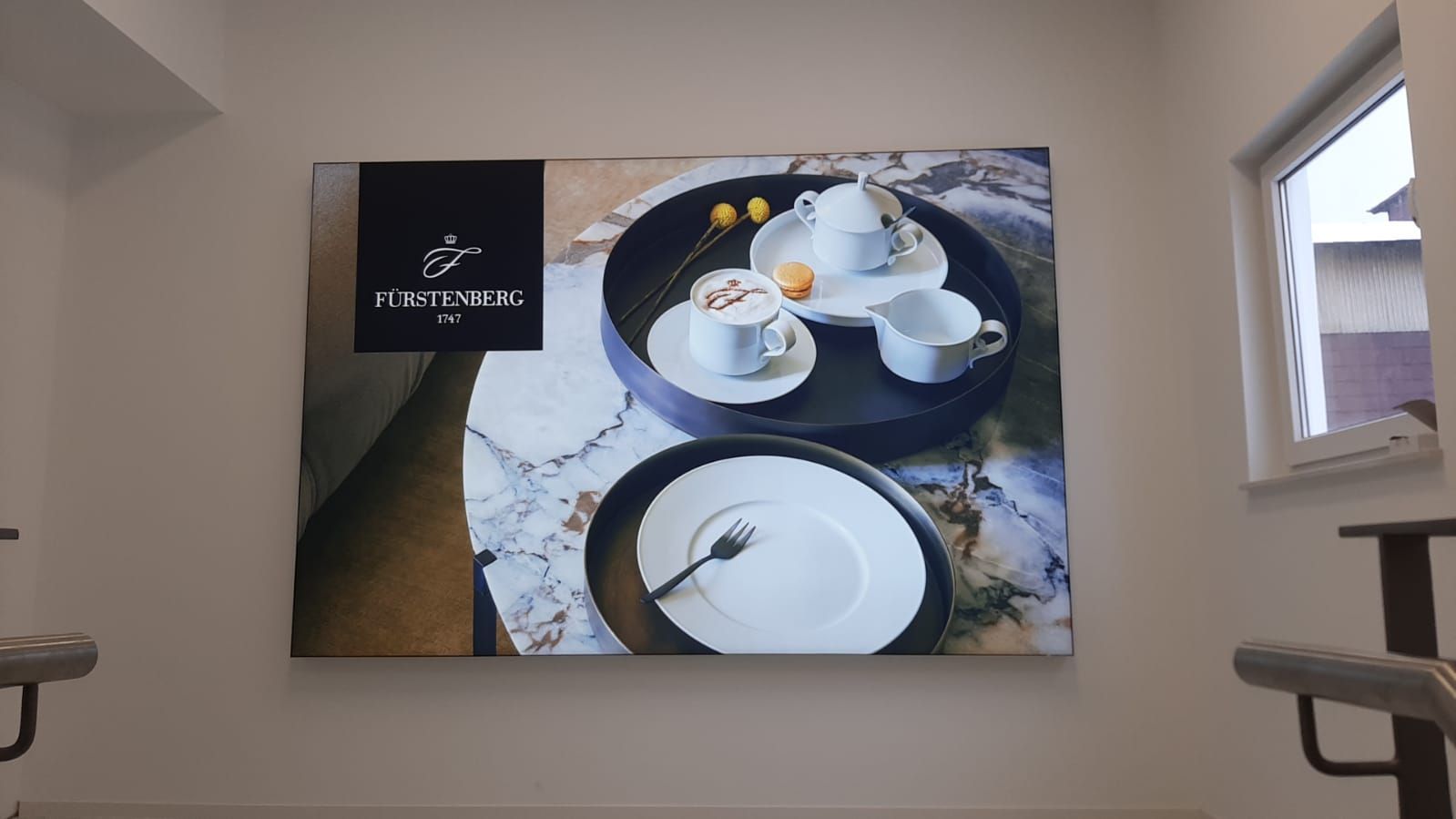 An einer Wand hängt ein großes Gemälde mit Tellern und Tassen.