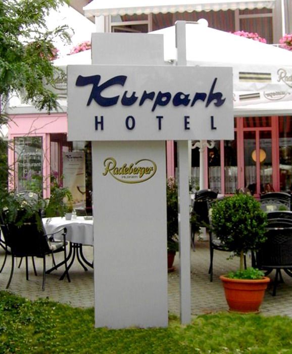 Ein Schild für das Kurpark Hotel steht vor einem Restaurant