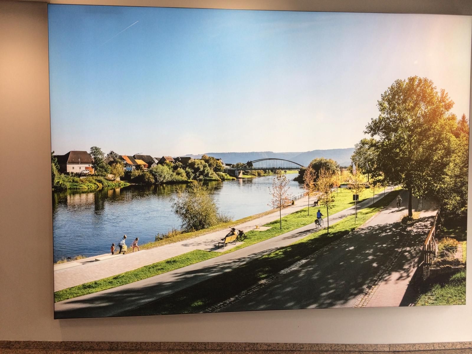 Ein großes Gemälde eines Flusses und einer Brücke an einer Wand.