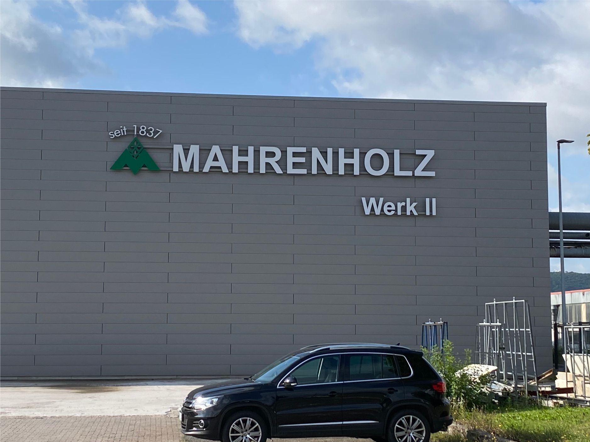 Ein schwarzes Auto parkt vor einem Gebäude mit der Aufschrift „Mahrenholz Werk II“.