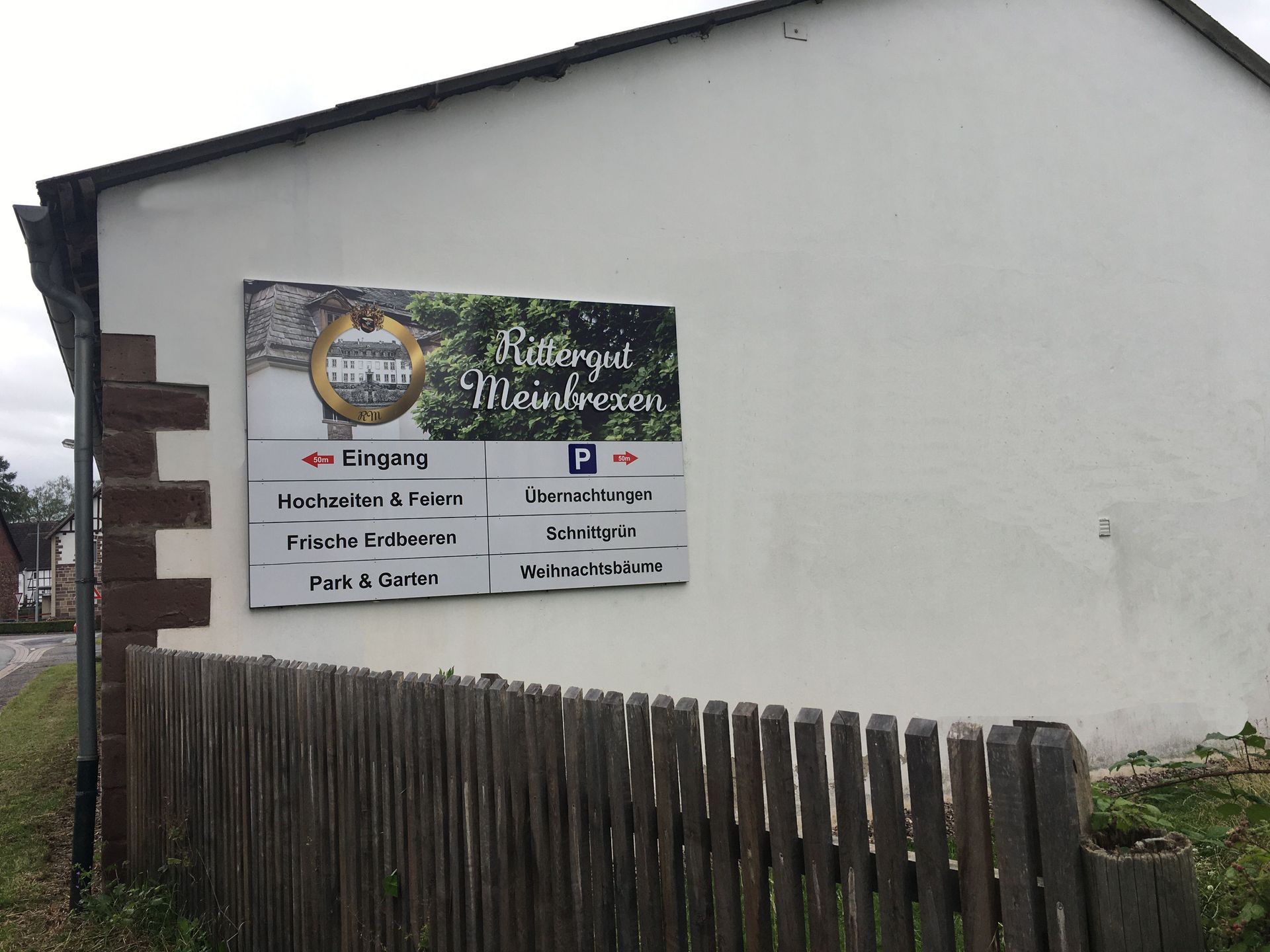 Ein Schild an der Seite eines Gebäudes mit einem Holzzaun davor.