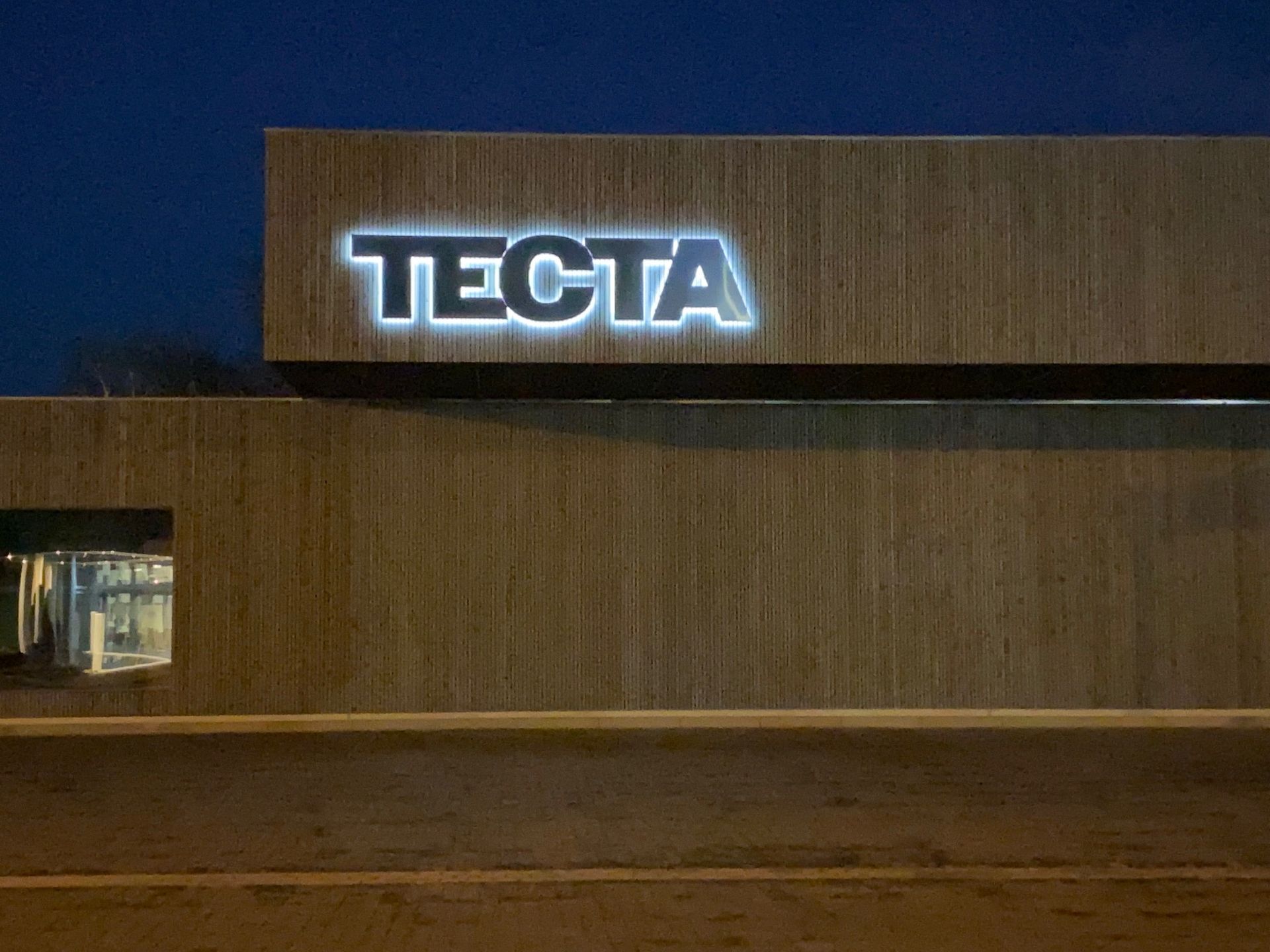 Ein Gebäude mit dem Wort Tecta darauf bei Nacht.