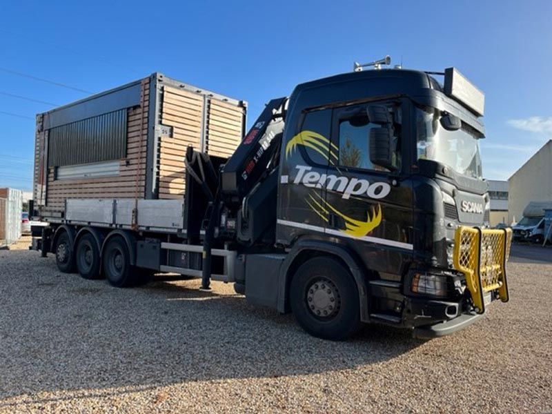 Porteur poids lourd avec grue qui transporte un préfabriqué 