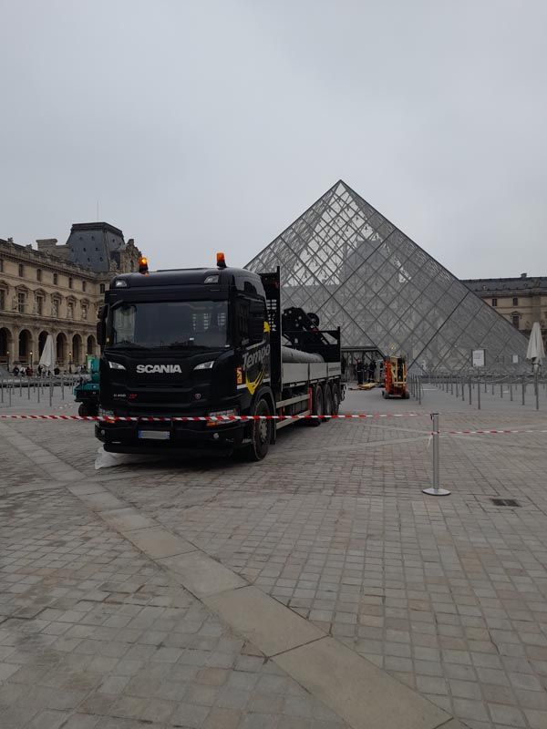 Un camion poids lourd à plateau stationné devant la pyramide du Louvres 
