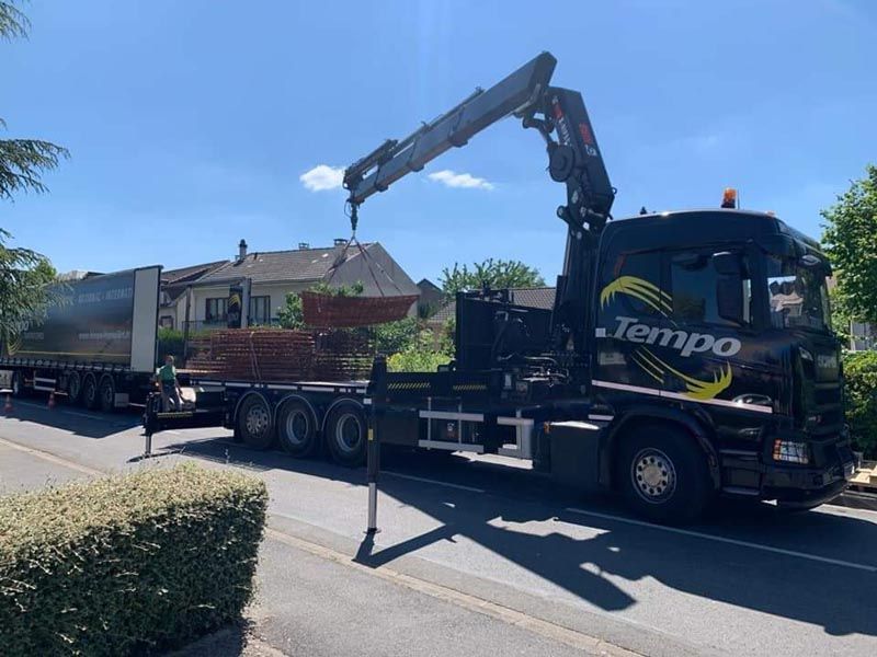 Camion poids lourd avec bras grue qui décharge des matériaux de construction
