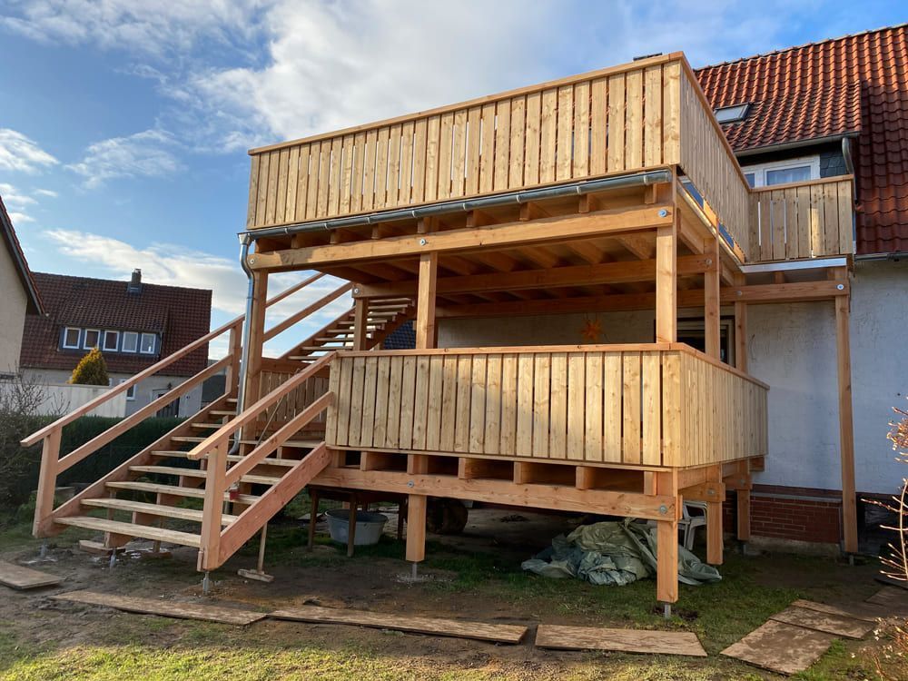 Vor einem Haus wird eine Holzterrasse mit Treppe gebaut.