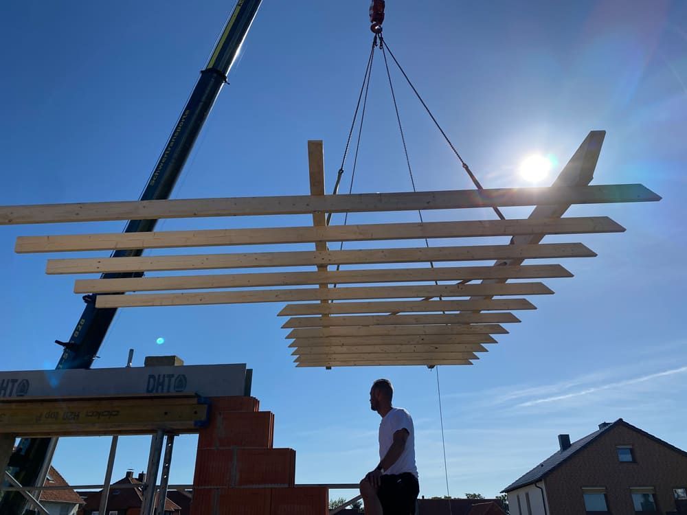 Ein Mann steht vor einem Kran und hebt eine Holzkonstruktion an