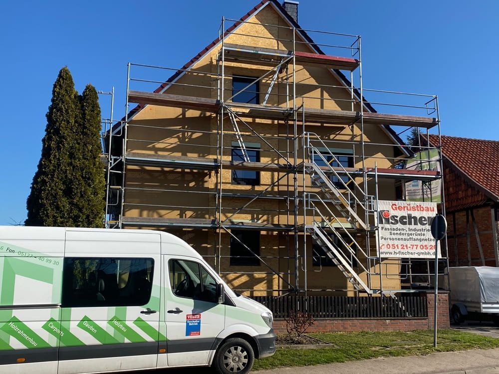 Vor einem Haus mit einem Gerüst steht ein Lieferwagen.