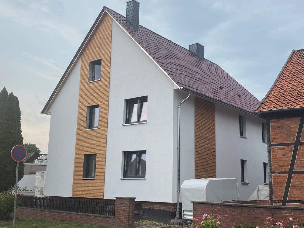 Ein weißes Haus mit einem braunen Dach hat ein Parkverbotsschild davor