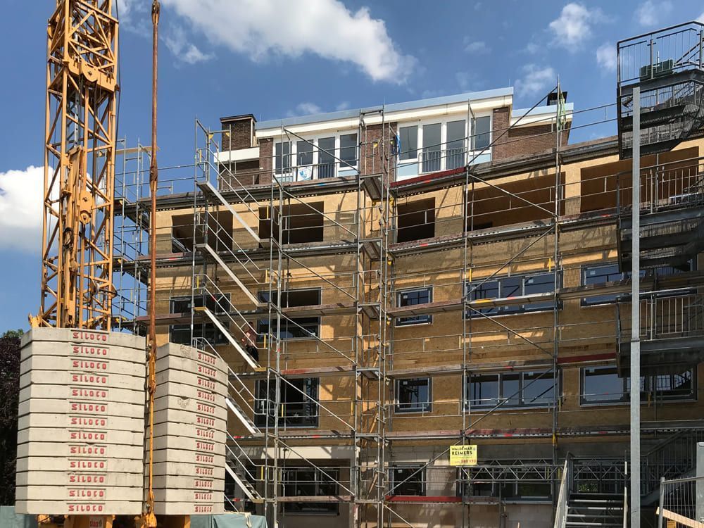 Ein im Bau befindliches Gebäude mit Gerüst und Kran im Hintergrund.