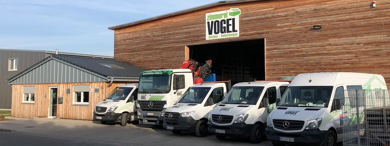 Vor einem Gebäude parkt eine Reihe Lieferwagen.